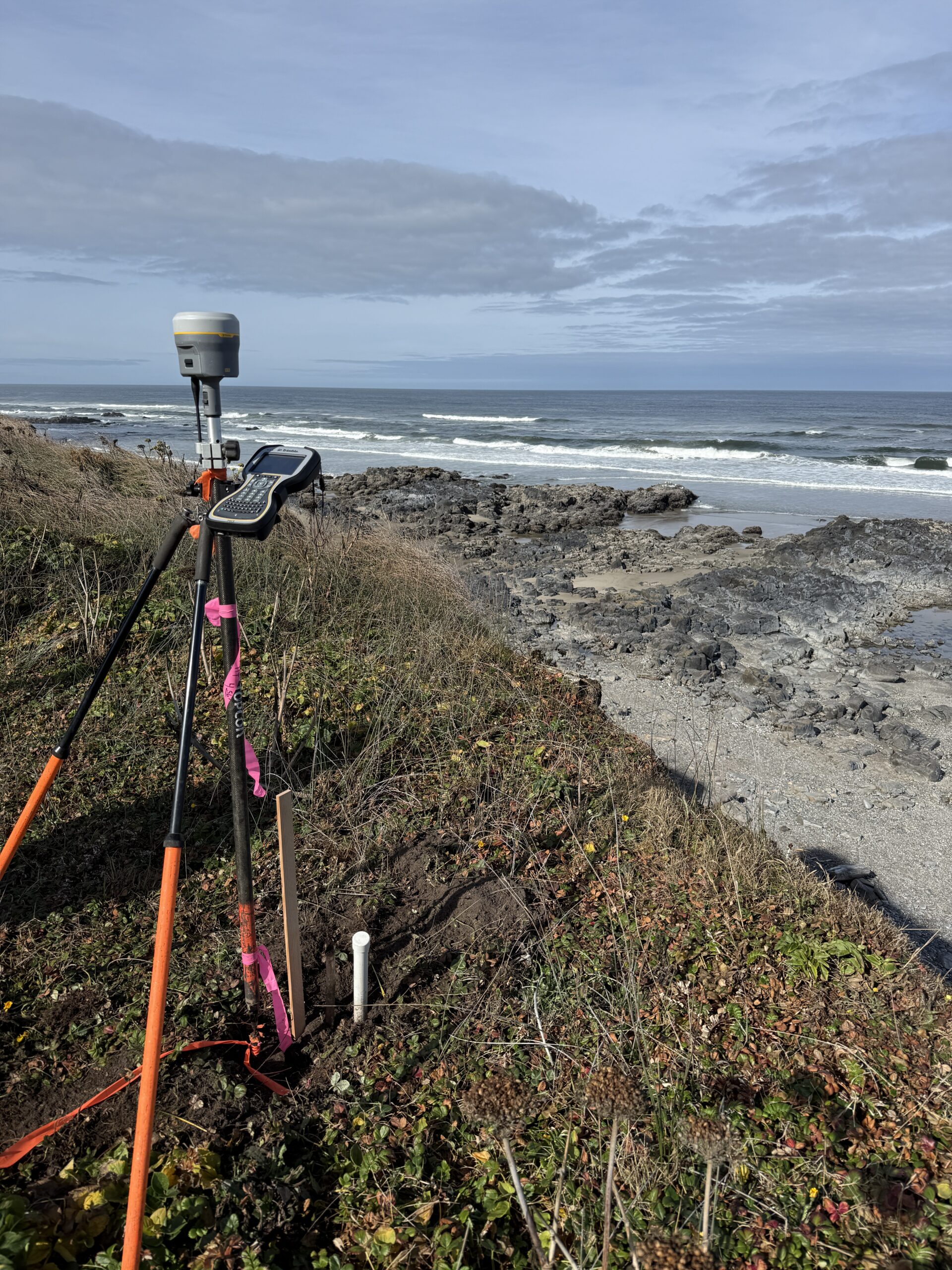 GPS surveying equipment is set up on a grassy cliff